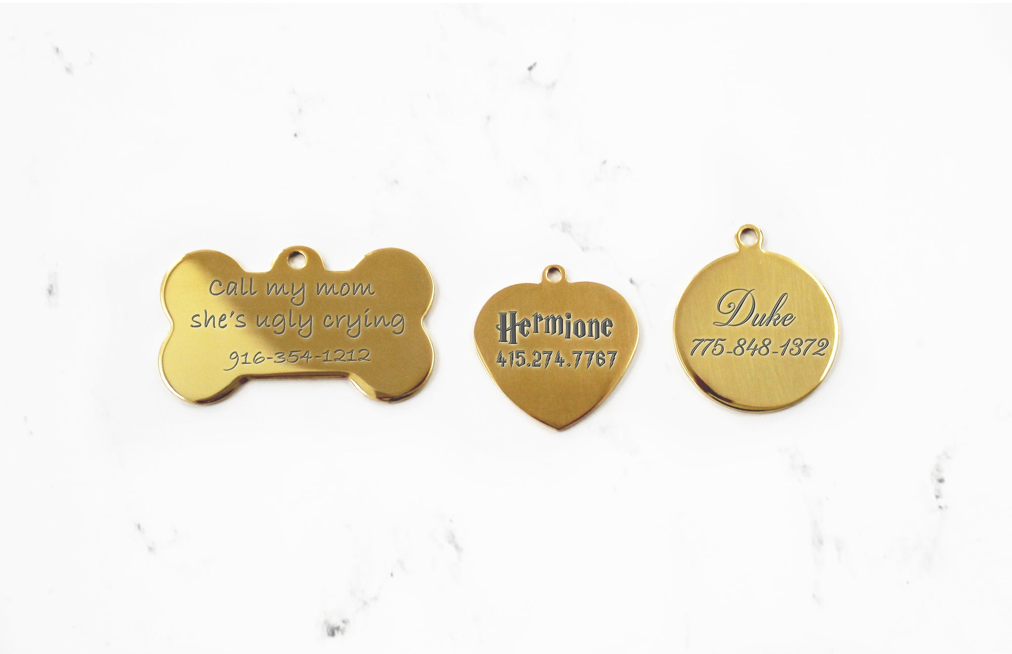 Engraved Gold Dog ID Tag with mirror finish in bone, heart and round shapes on a white marble background
